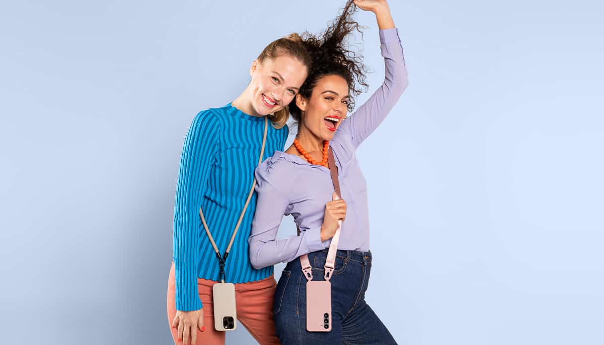 Zwei weibliche Models lächeln und tragen jeweils eine Handyhülle mit einem Band daran.
