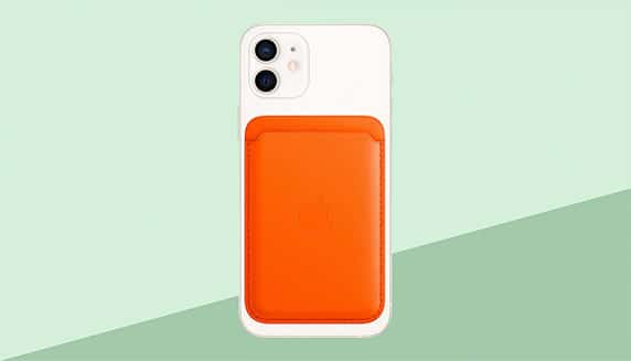 Weißes iPhone mit orangefarbener MagSafe-Ledertasche, grüner Hintergrund.