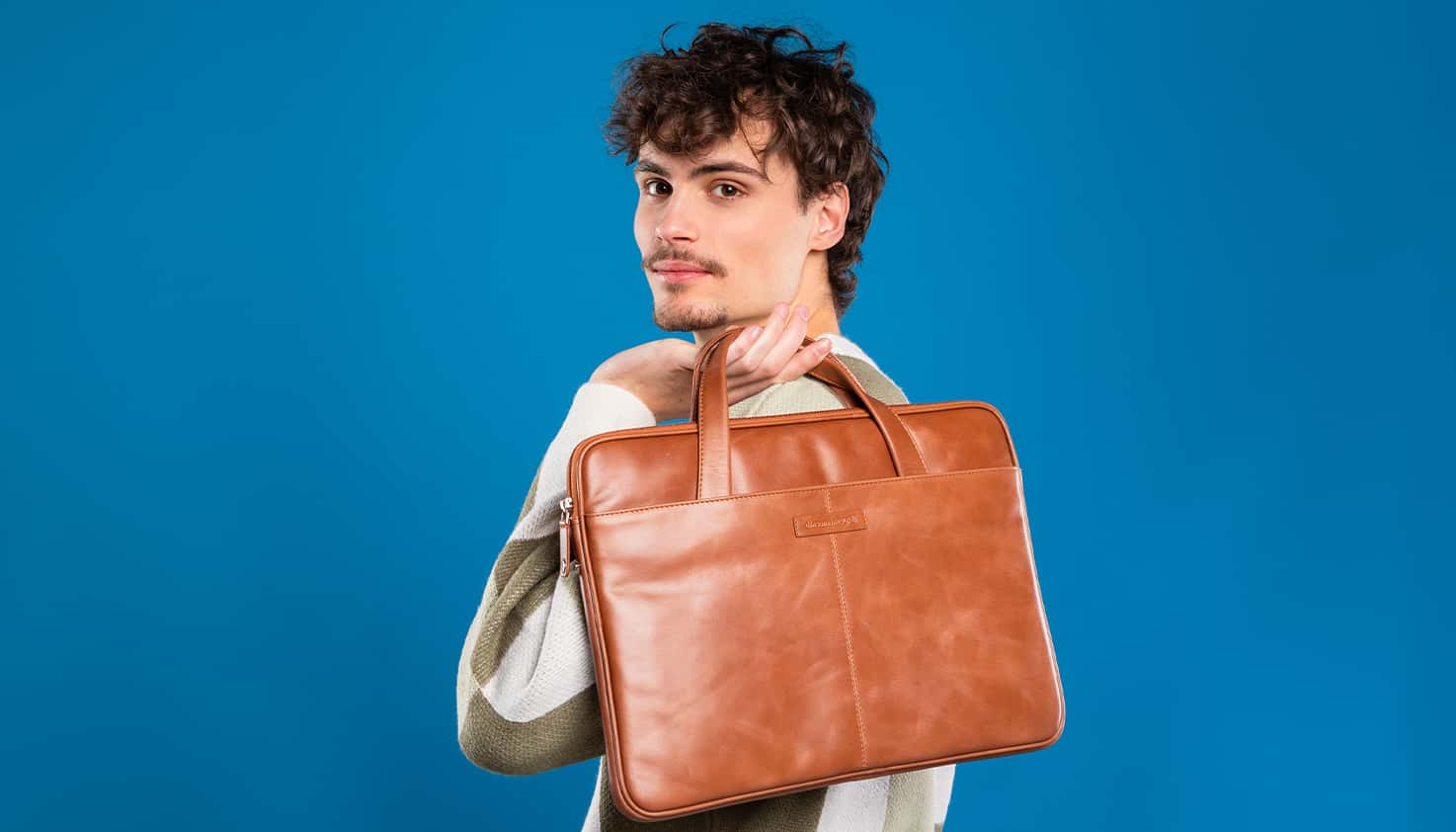 Ein Mann trägt eine echte Leder-Laptoptasche von Dbramante über der Schulter und hält sie mit der Hand.