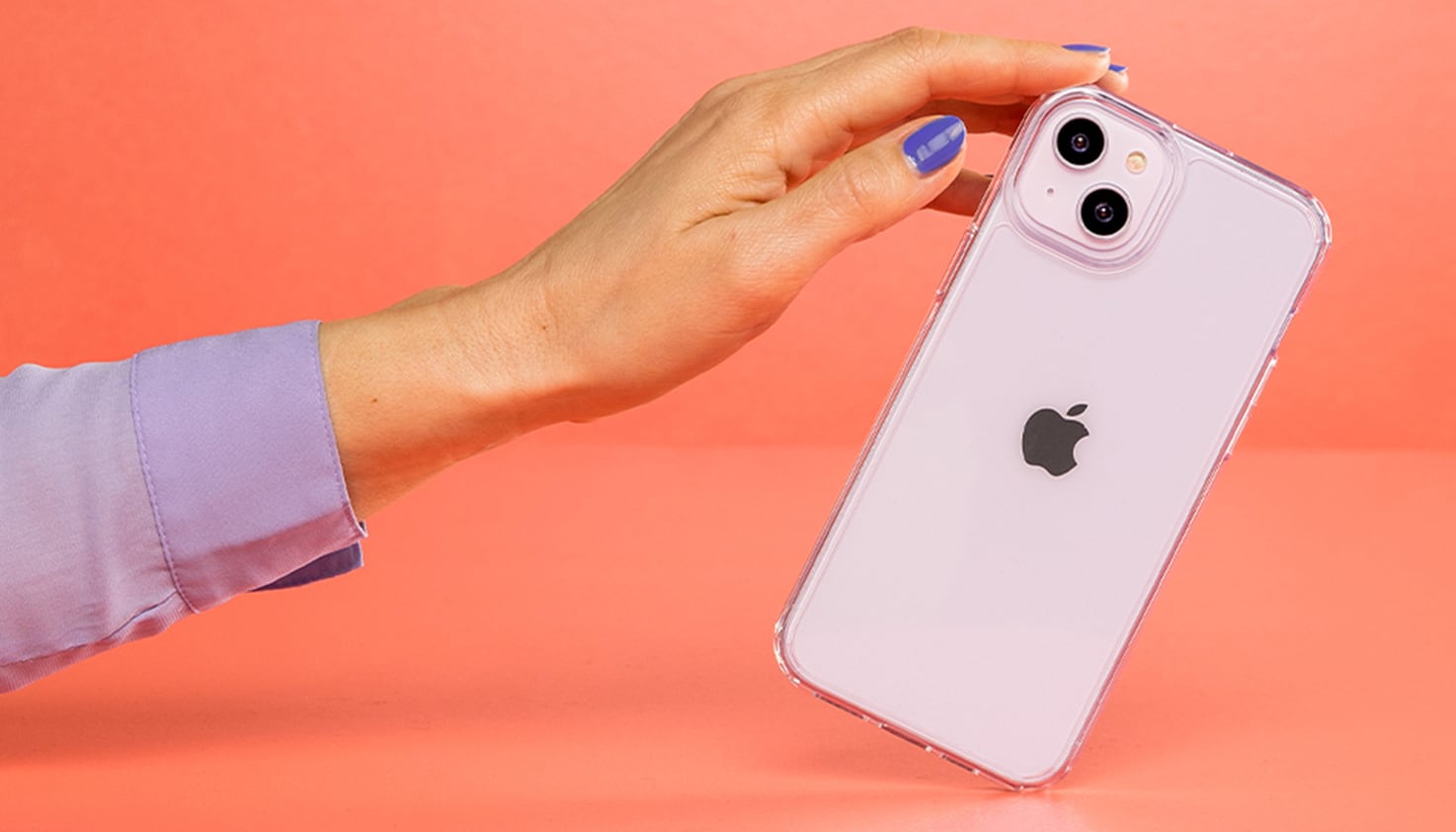 Eine Frauenhand, die ein iPhone hält, der Hintergrund ist orange.